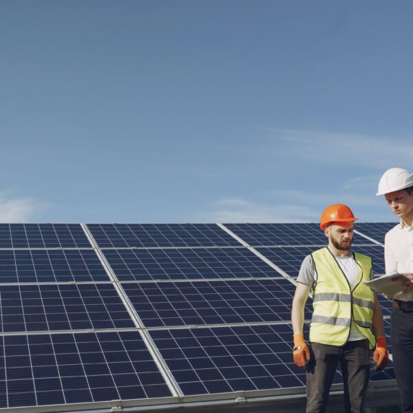 Two men in hard hats standing in front of solar panels